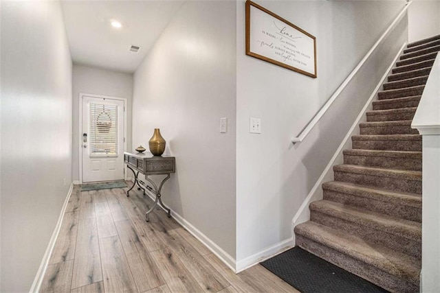 staircase featuring wood finished floors, baseboards, visible vents, and recessed lighting