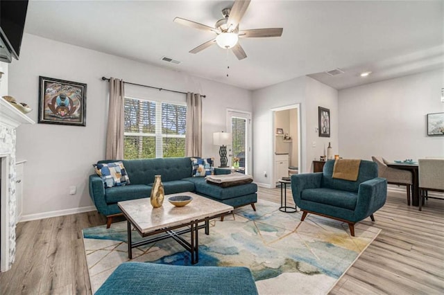 living area featuring visible vents, ceiling fan, wood finished floors, and baseboards