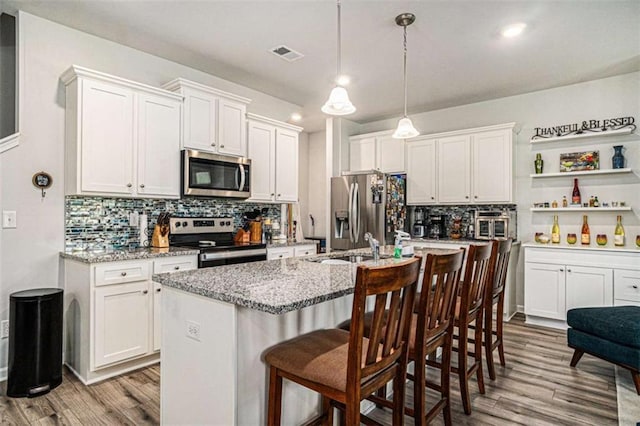 kitchen featuring backsplash, white cabinetry, wood finished floors, and stainless steel appliances