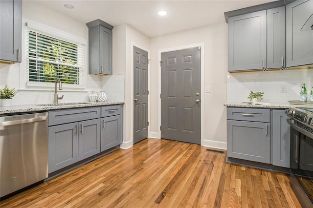 kitchen featuring dishwasher, a sink, gray cabinets, range, and recessed lighting