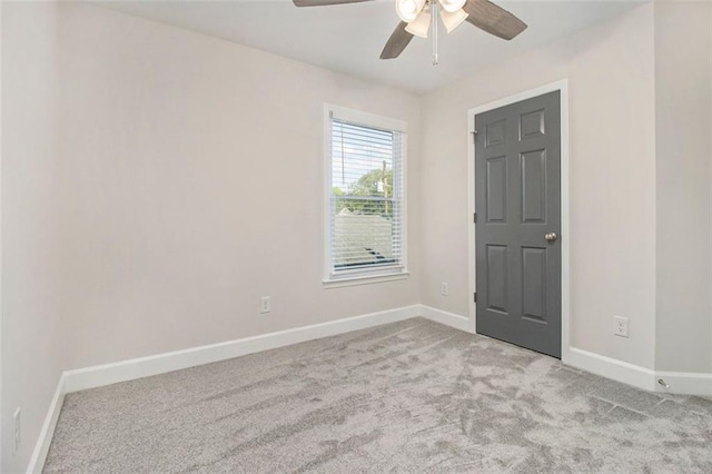 carpeted spare room featuring baseboards and a ceiling fan