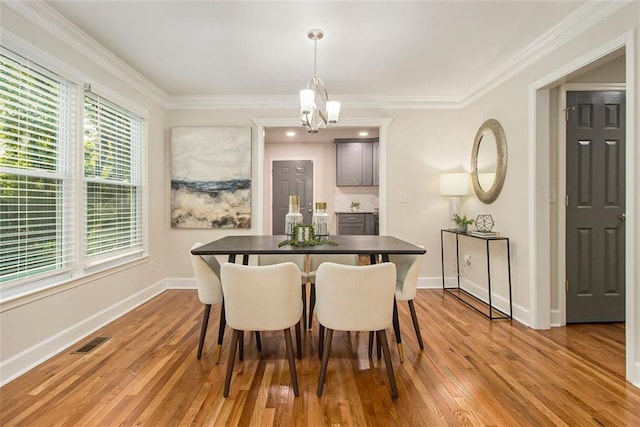 dining area featuring a chandelier, light wood-style floors, baseboards, and ornamental molding