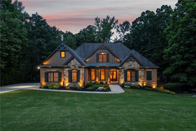craftsman-style home with stone siding, a porch, a lawn, and board and batten siding