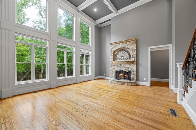 unfurnished living room featuring a towering ceiling, stairway, beam ceiling, a fireplace, and coffered ceiling
