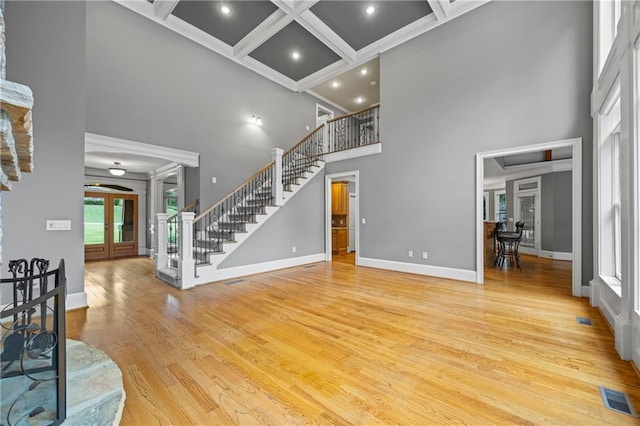 unfurnished living room featuring french doors, a high ceiling, stairway, coffered ceiling, and baseboards