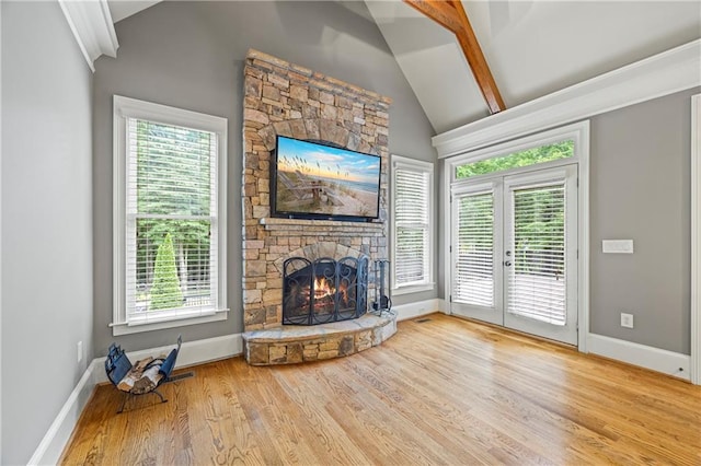 unfurnished living room featuring lofted ceiling, wood finished floors, a fireplace, french doors, and baseboards