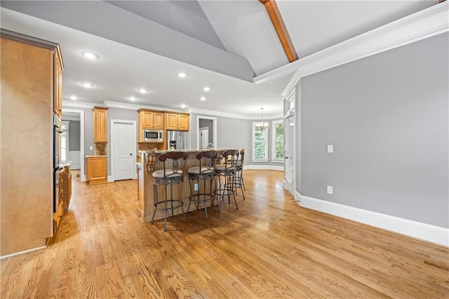 kitchen with appliances with stainless steel finishes, lofted ceiling, a kitchen breakfast bar, ornamental molding, and recessed lighting
