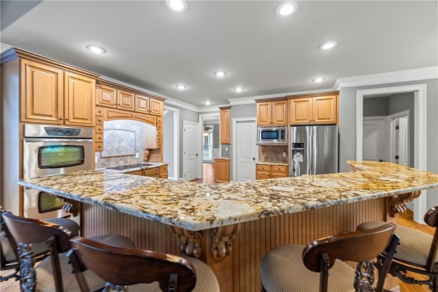 kitchen featuring stainless steel appliances, crown molding, a breakfast bar, decorative backsplash, and recessed lighting