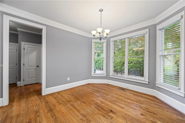 unfurnished dining area featuring a chandelier, baseboards, ornamental molding, and light wood finished floors