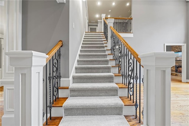 stairs with wood finished floors, recessed lighting, a towering ceiling, and baseboards
