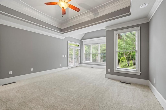 carpeted empty room with ornamental molding, a raised ceiling, plenty of natural light, and ceiling fan