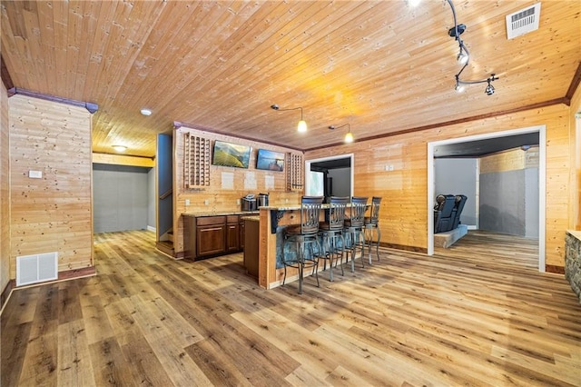 kitchen with wood ceiling, a kitchen breakfast bar, light wood-style flooring, wood walls, and baseboards