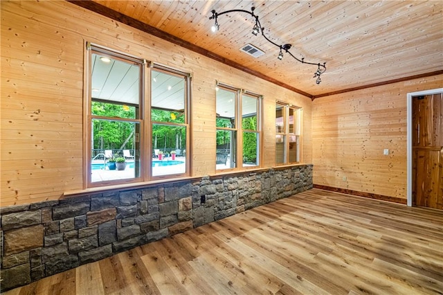 unfurnished room featuring wood finished floors, track lighting, and wooden walls