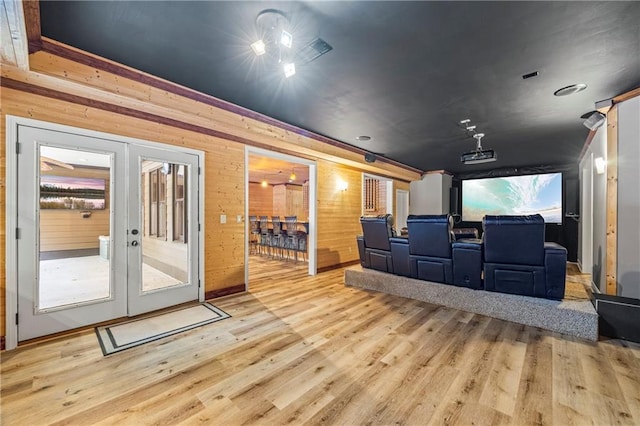 cinema room with wood finished floors, wooden walls, and french doors