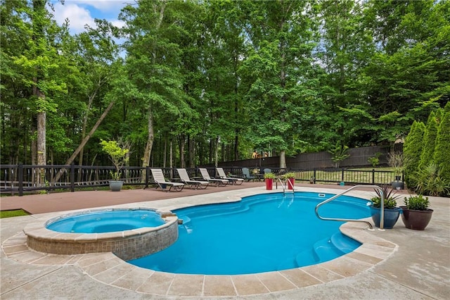 view of pool featuring a fenced backyard, a pool with connected hot tub, a patio area, and view of scattered trees