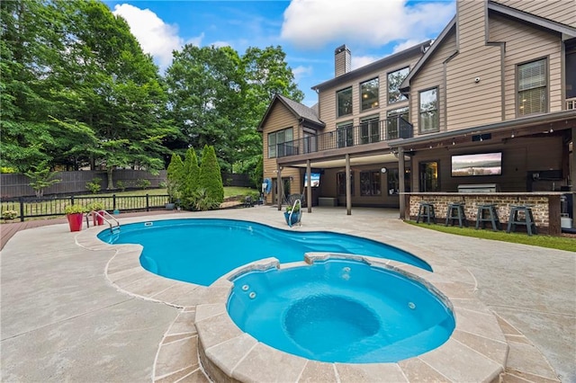 view of pool featuring a patio, fence, and a pool with connected hot tub