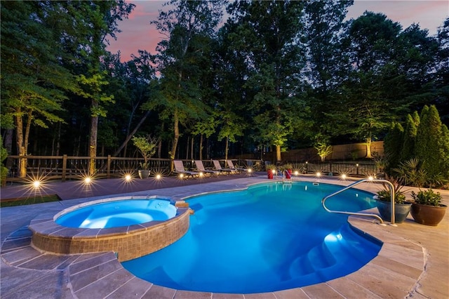pool at dusk with a fenced backyard and a pool with connected hot tub