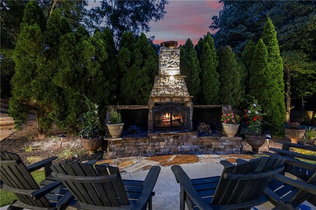 patio terrace at dusk featuring an outdoor stone fireplace