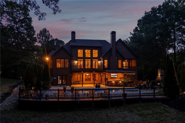 back of house at dusk with a wooden deck