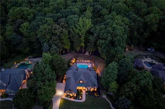 aerial view of property and surrounding area with a forest and a pool area