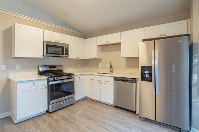 kitchen featuring appliances with stainless steel finishes, sink, light hardwood / wood-style flooring, and white cabinets