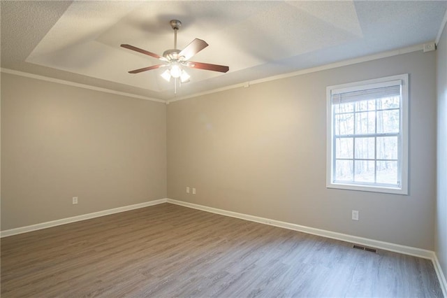 empty room featuring hardwood / wood-style floors, ornamental molding, a raised ceiling, and ceiling fan