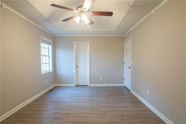 interior space with crown molding, a tray ceiling, wood-type flooring, and ceiling fan