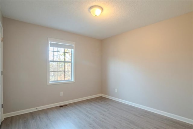 spare room featuring light hardwood / wood-style floors and a textured ceiling