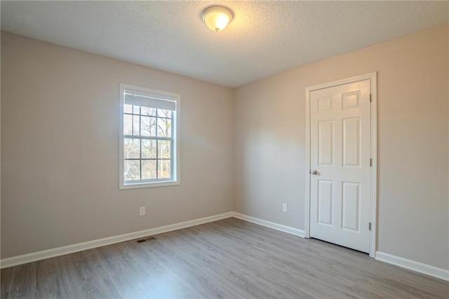 empty room featuring a textured ceiling and light wood-type flooring