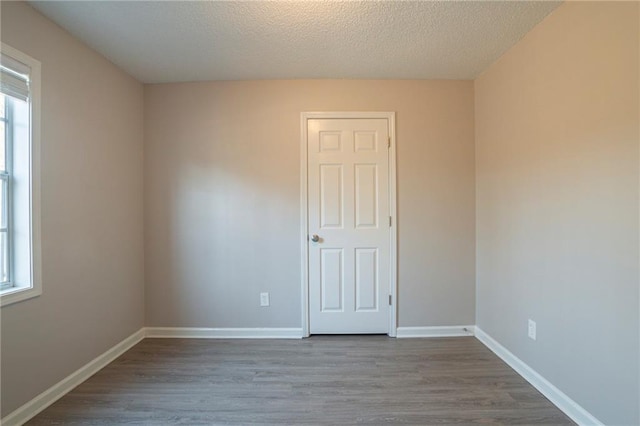 unfurnished room featuring hardwood / wood-style flooring, a wealth of natural light, and a textured ceiling