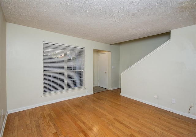 spare room featuring a textured ceiling and light hardwood / wood-style flooring