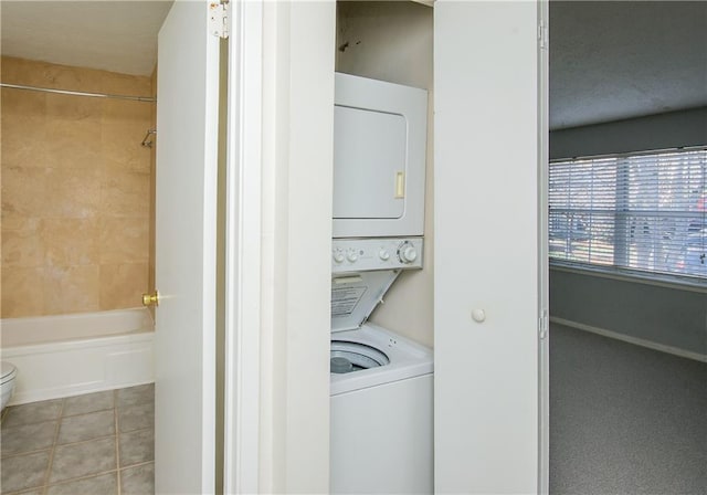 laundry room with tile patterned floors and stacked washer / dryer