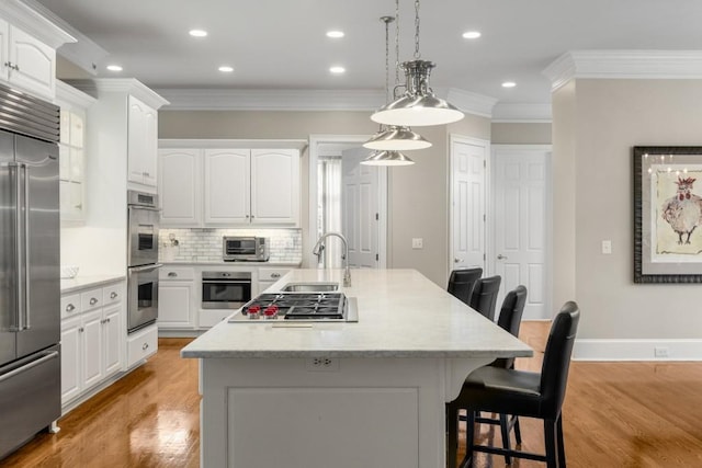 kitchen with white cabinetry, sink, decorative light fixtures, and appliances with stainless steel finishes