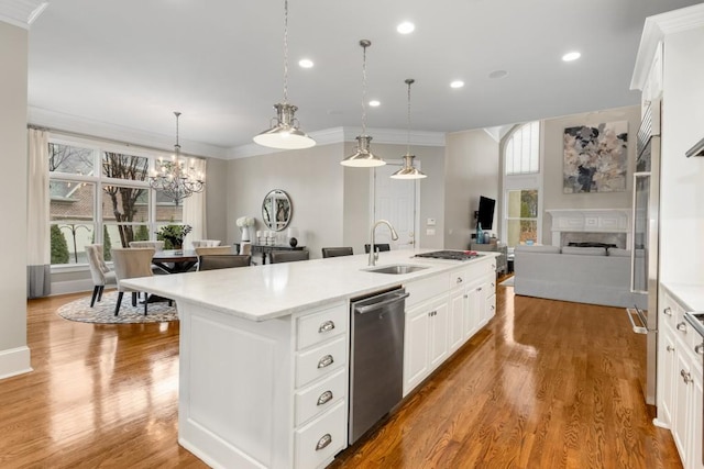 kitchen featuring decorative light fixtures, white cabinetry, dishwasher, sink, and a kitchen island with sink