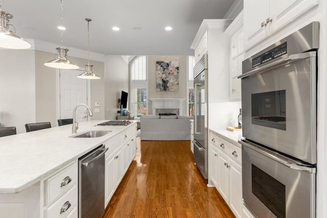 kitchen with pendant lighting, stainless steel appliances, sink, and white cabinets