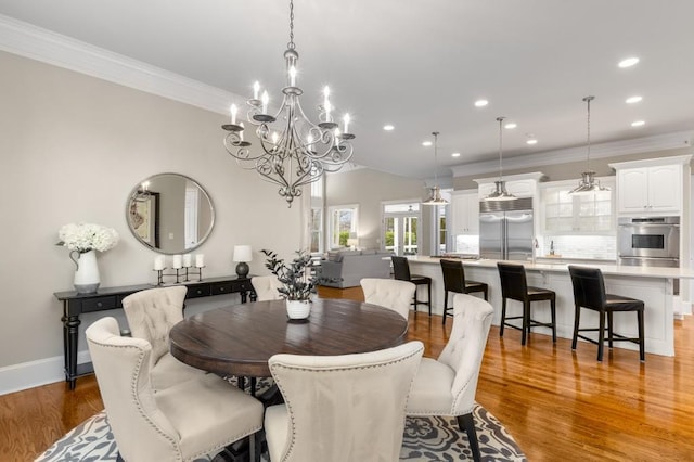 dining room featuring sink, wood-type flooring, and ornamental molding