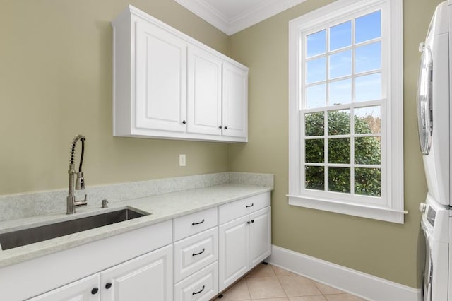 laundry room featuring light tile patterned flooring, sink, stacked washer and dryer, cabinets, and crown molding