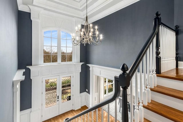 stairs featuring crown molding, wood-type flooring, french doors, and a chandelier