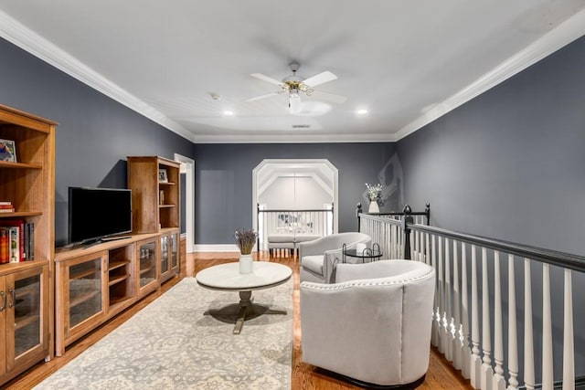 living area featuring hardwood / wood-style flooring, ceiling fan, and ornamental molding