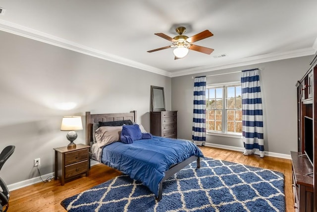 bedroom with hardwood / wood-style flooring, ornamental molding, and ceiling fan