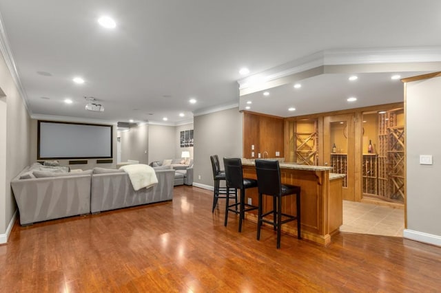 kitchen featuring ornamental molding, a kitchen bar, kitchen peninsula, and light hardwood / wood-style flooring