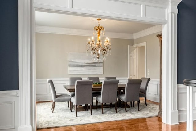 dining area with wood-type flooring, a notable chandelier, and crown molding