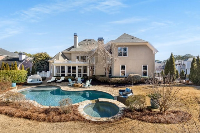 rear view of house featuring an in ground hot tub and a sunroom