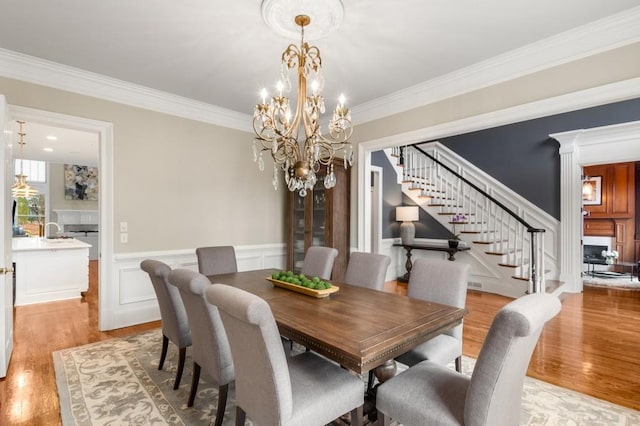 dining room with sink, crown molding, light hardwood / wood-style floors, and a chandelier