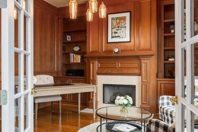 living area featuring built in shelves, dark hardwood / wood-style floors, and french doors