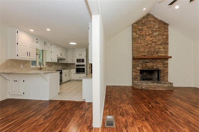 kitchen featuring light stone counters, kitchen peninsula, white cabinetry, and stainless steel appliances