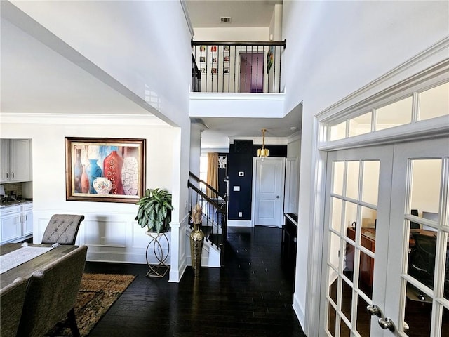 foyer with crown molding, a towering ceiling, and dark hardwood / wood-style flooring