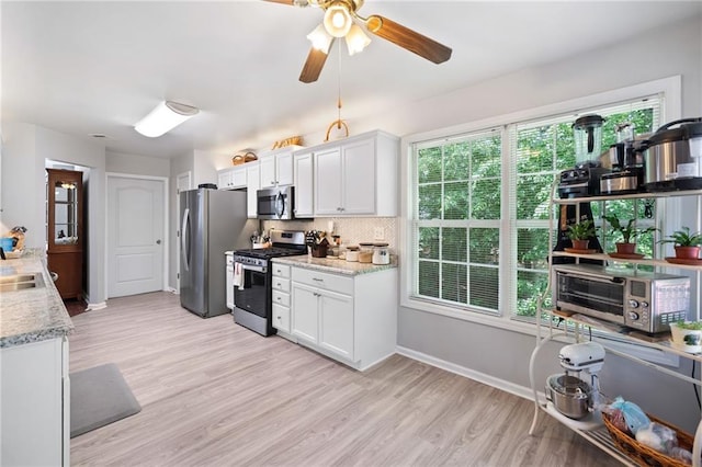 kitchen featuring appliances with stainless steel finishes, white cabinets, light wood-style flooring, and tasteful backsplash