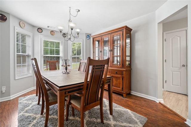 dining room with a chandelier, baseboards, and wood finished floors