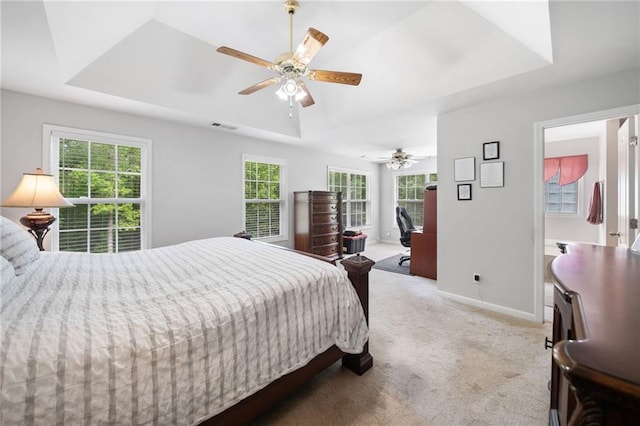 carpeted bedroom with a tray ceiling, baseboards, and ceiling fan